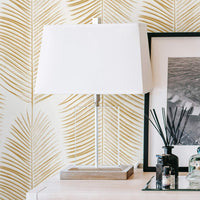 faux gold big palm leaves design wallpaper in bedroom setting