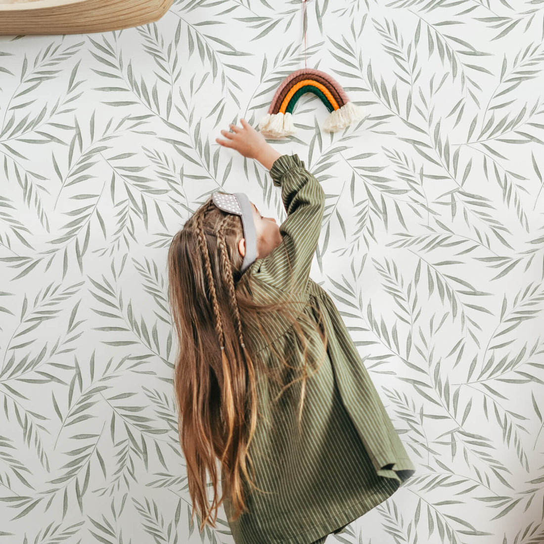 modern bohemian girls room interior with green botanical removable wallpaper and rainbow tassel decor