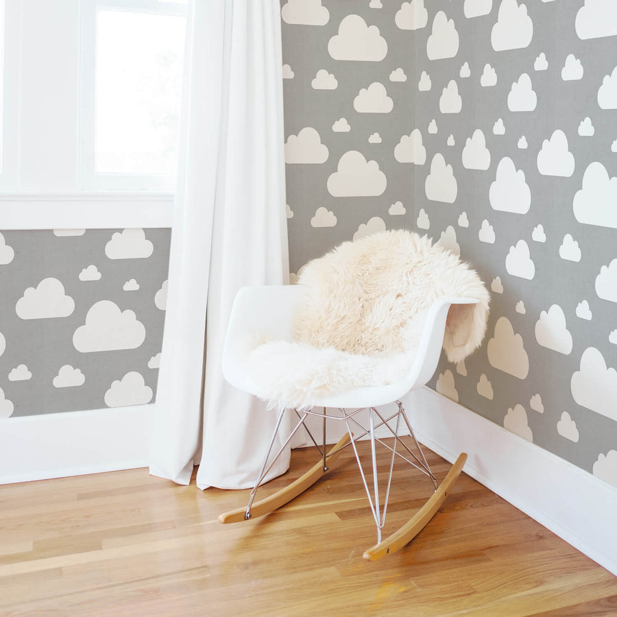 Grey and white cloud pattern wallpaper in soft gender neutral nursery interior with white curtains and wooden flooring